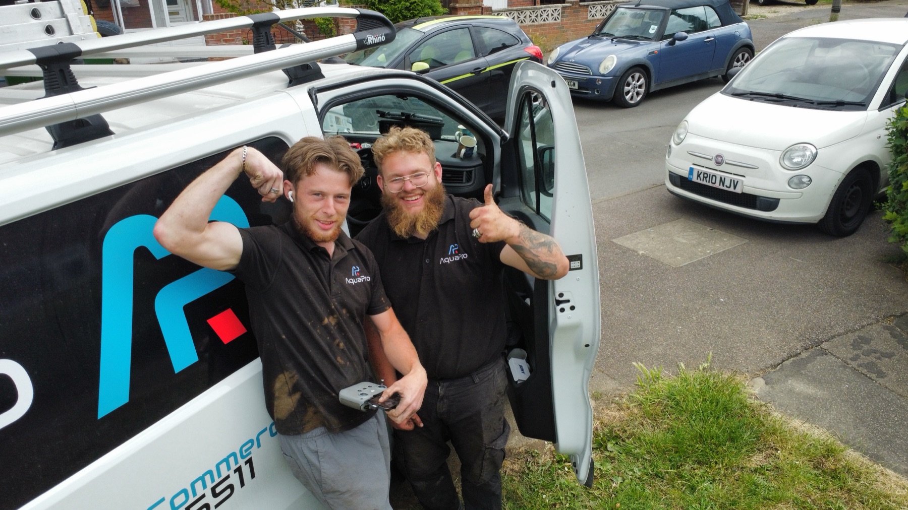 Two AquaPro cleaners in work polos giving a thumbs up beside the AquaPro van